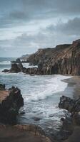 Rugged Coastal Cliffs with Crashing Ocean Waves and Moody Sky in a Remote Natural Setting photo