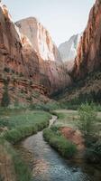 Majestic Red Rock Canyon with Lush Greenery and Serene Stream under Clear Sky in Natural Landscape photo