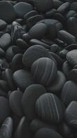 Closeup of Smooth Black River Stones with Natural White Patterns and Texture in a Dark Background photo