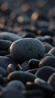 Closeup of Smooth Black Pebbles in Warm Light on Rocky Beach Representing Calmness and Nature photo