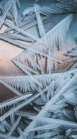 Closeup of sharp triangular ice crystals with natural patterns on smooth metallic background in winter photo