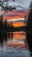 Scenic View of Vibrant Orange and Purple Sunset Reflecting on Calm Forest Lake with Pine Trees Silhouette photo