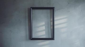 Empty Black Frame on Gray Concrete Wall with Natural Light and Shadow Patterns photo