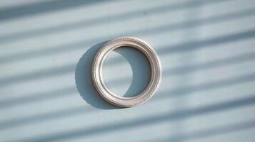 Minimalist White Circular Picture Frame Hanging on Light Blue Wall with Shadow Patterns from Window Blinds photo