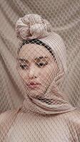 Artistic Portrait of Woman with Neutral Tones Wrapped in Textured Mesh Fabric and Minimal Background photo