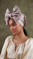 Elegant Woman Wearing Satin Bow Headwrap and Cream Blouse Against Green Textured Background photo