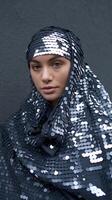 Portrait of Woman Wearing Shiny Sequin Hijab Against Dark Textured Background with Confident Expression photo