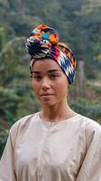 Portrait of Woman Wearing Colorful Patterned Headwrap in Nature with Calm Expression and Greenery Background photo