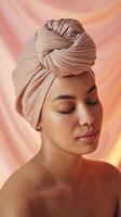 Serene Woman with Neutral Toned Head Wrap and Bare Shoulders Against Soft Peach Background photo