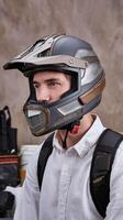 Man Wearing Futuristic Matte Gray Helmet with Metallic Details Indoors Against Neutral Background photo