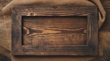 Rustic Wooden Frame with Burnt Grain Texture on Burlap Fabric and Wooden Surface Background photo