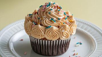 Vanilla Cupcake with Swirled Buttercream Frosting and Colorful Sprinkles on White Plate photo