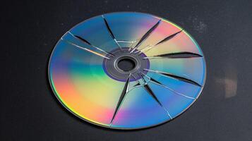Shattered Compact Disc with Rainbow Reflections on Dark Black Surface Representing Fragility and Obsolescence photo