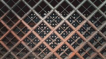 Rustic Metal Grid Fence with Diagonal Pattern and Light Effects Against Dark Background photo
