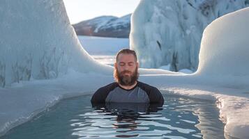 Man with Beard Meditating While Immersed in Icy Water Surrounded by Frozen Ice Formations and Mountains photo