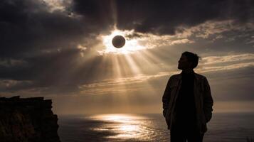 Silhouette of Person Standing by Ocean at Sunset Overhead Solar Eclipse with Dramatic Clouds photo