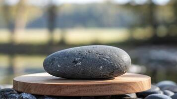 Smooth Gray Stone on Wooden Base with Nature Background Representing Balance and Tranquility Outdoors photo