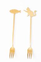 Two golden forks with decorative handles featuring cat and fish shapes, isolated on a white background photo