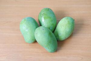 Mango fruit on wooden background, closeup of green mango fruit photo