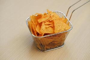 nachos papas fritas en un metal cesta en un de madera mesa foto