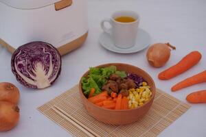 A colorful dish featuring red rice, meat, corn, carrots, lettuce, and a sunny-side-up egg photo