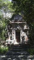 Traditional Balinese temple gate with intricate stone carvings and guardian statues surrounded by lush greenery and natural light in a serene outdoor setting in Bali photo