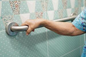 Asian elderly old woman patient use toilet support rail in bathroom, handrail safety grab bar, security in nursing hospital. photo