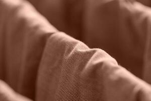 Close up view of wavy brown corduroy fabric texture in soft focus with warm lighting. photo