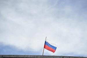 Russian flag on building top against clear sky with light clouds in daytime. photo