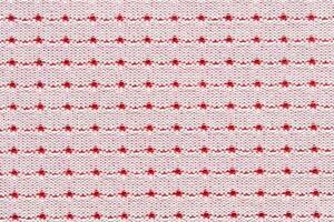 Red and white dotted pattern on knitted fabric background with repeating horizontal lines. photo