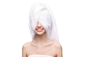 Young caucasian female with towel wrapped around head smiling, white background. photo