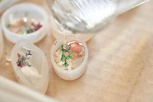 Crafting resin art with dried flowers and shells in molds on beige surface. photo