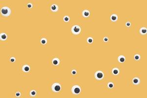 Scattered googly eyes on yellow background with playful and creative design elements. photo