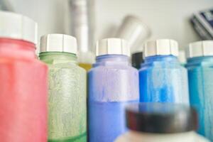 Colorful array of plastic paint bottles in a row on shelf closeup with focus on shapes and textures. photo