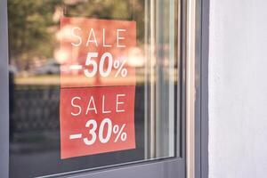 Storefront window display with red sale signs offering 50 and 30 discounts during seasonal clearance event. photo
