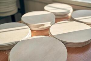Sunlit wooden circles stacked on table in workshop with natural light shadows. photo