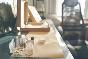 Crafting workspace with open cardboard boxes and assorted art supplies on a sunlit table. photo