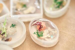 Handmade resin decorations with seashells and coral embedded in oval molds for unique coastal themed art and craft projects. photo