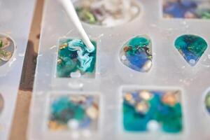 Crafting resin art. creating colorful ocean inspired jewelry with silicone molds and epoxy techniques. photo
