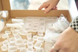 Hands crafting jewelry with silicone molds and resin in artistic workspace. photo