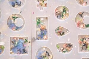 Creative resin art with colorful shells and decorative elements in mold shapes. photo