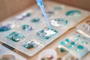 Close up of resin art process with colorful designs and pipette application on molded shapes. photo