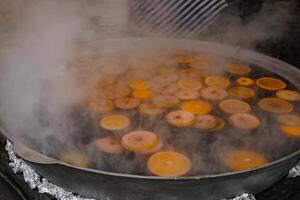 mulled wine with apples and oranges is brewed in a street food cauldron photo