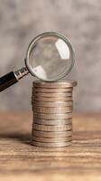 Stacked coins under magnifying glass, assessing value and detail photo