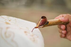 close up of hand hold canting is tool for make batik with isolated white background. Canting batik is tools to make batik. canting batik is used to put wax. canting consists of three type. photo