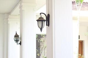 close up view of single classic black lamp or lantern on white wall with copy space. photo