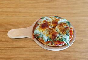 Spinach and cheese pizza, Italian food, on a wooden table. photo