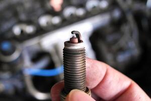 Close up of used spark plug in hand , car spark plug for engine ignition system , Automotive parts concept photo