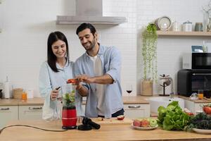 Young couple mixing fruit in a food processor, making a smoothie. Husband and wife having fun with smoothie in the kitchen and looking at each other. photo