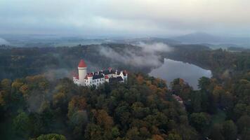 Aerial orbiting view of foggy chateau Konopiste and pond in Czechia in October 2024 video
